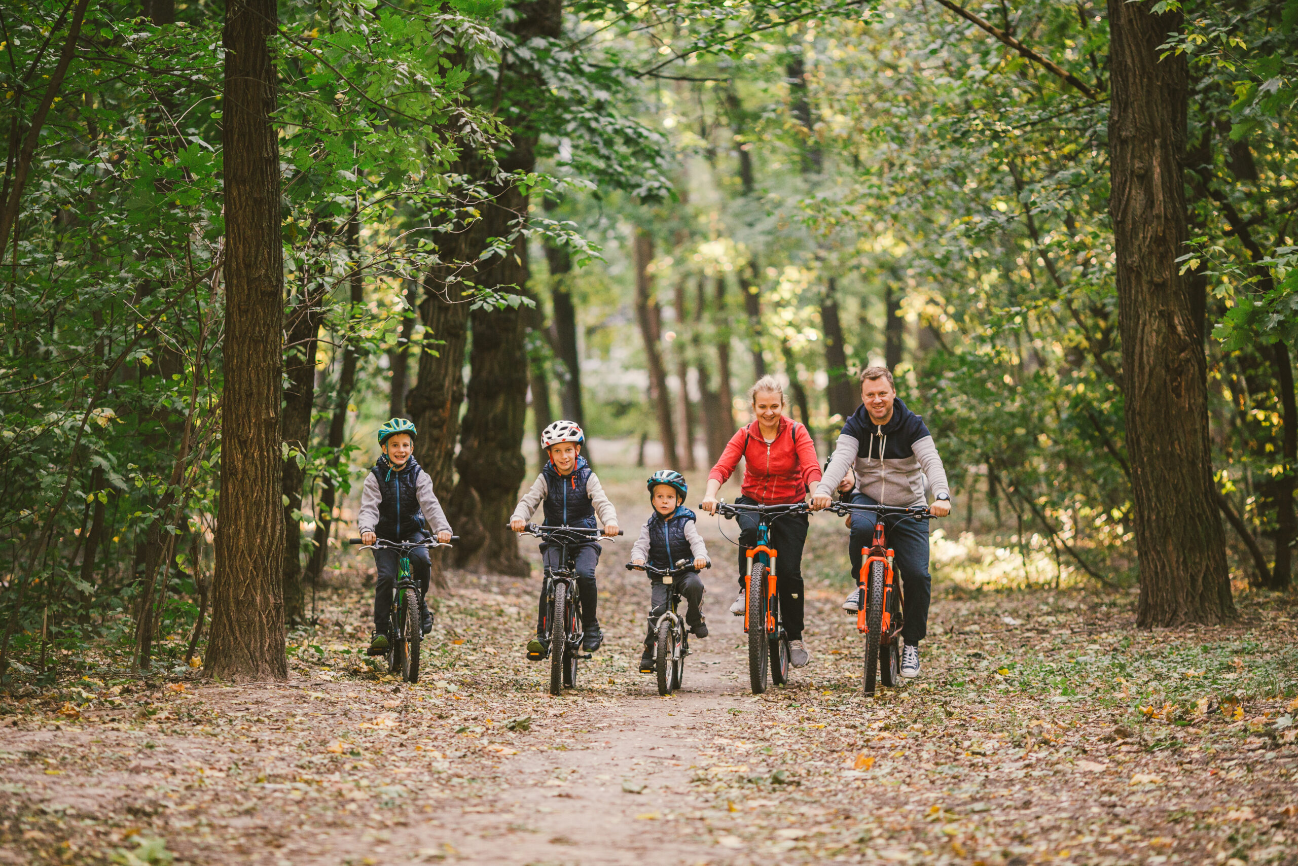 parents and kids cycling on forest trail. Young family cycling in autumn park. Family mountain biking on forest. Theme family active sports outdoor recreation. Family Cycling Through Fall Woodland